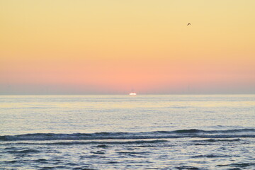 Sunset near Noordwijk beach, with the horizon filled with hardly visible wind turbines   