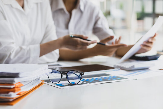 Colleagues work on paperwork on their desks. Businesswoman discussing business project project documents in office.