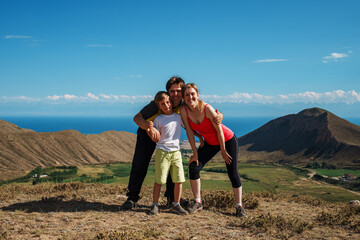 Happy family of hikers posing on top of the mountain