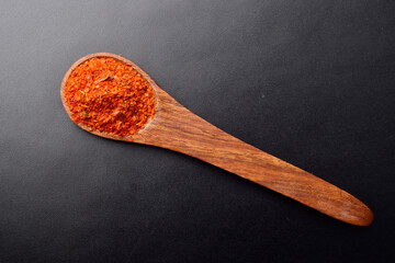 Top view of ground chili in spoon on dark background