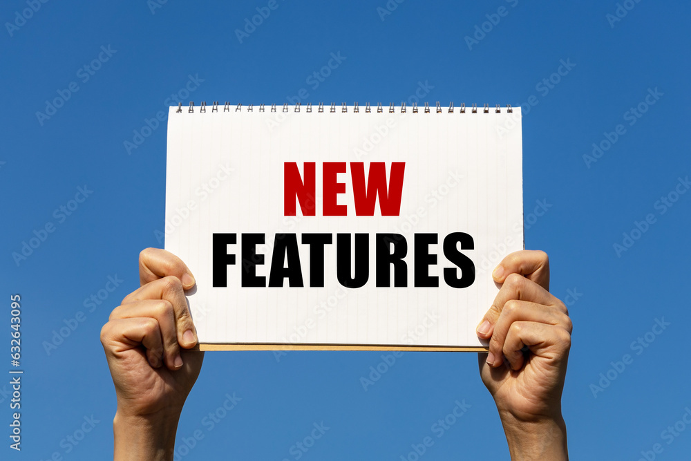 Poster new features text on notebook paper held by 2 hands with isolated blue sky background. this message 