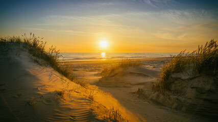 Weg zwischen den Dünen führt zum Strand bei Sonnenuntergang