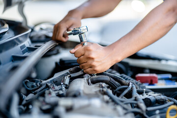 Auto mechanic repairman using a socket wrench working engine repair in the garage, changing spare parts, checking the mileage of the car, checking and maintenance service concept.