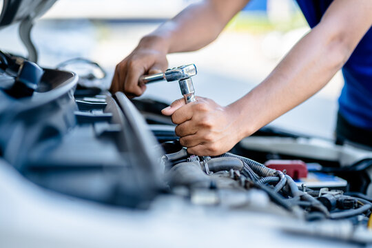 Auto mechanic repairman using a socket wrench working engine repair in the garage, changing spare parts, checking the mileage of the car, checking and maintenance service concept.