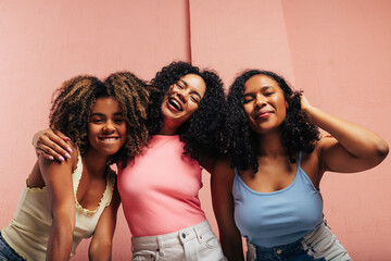 Three laughing females with curly hair having fun and looking at camera
