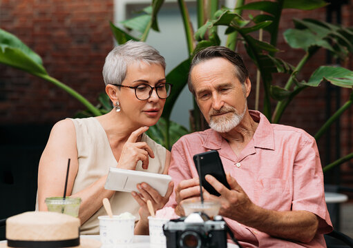 Mature couple using their smartphones while sitting outdoors