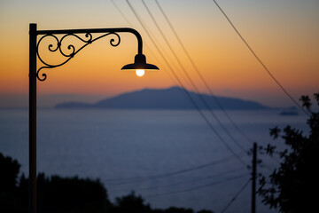 Silhouette of nostalgic street lantern with sunset panorama in Anacapri village on Capri Island...