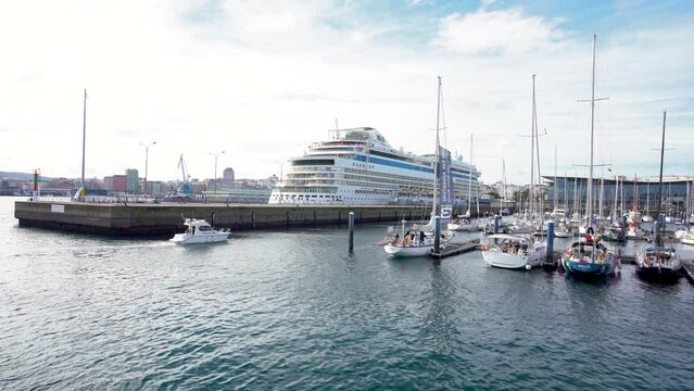 A Coruna, SPAIN - October 30 2022: View of spectacular Marina Real Port. Beautiful AIDA cruise docked in the bay. Yachts and fishing boats. Travel destination in Galicia. Stabilized static footage.