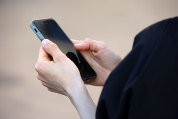 Smartphone in hands of woman on city street in summer, online communication