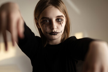 Little girl with spooky Halloween makeup looking at camera like zombie. Creepy kid's portrait.