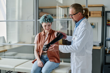 Portrait of young woman with colored hair smiling during prosthetic fitting in orthology clinic,...