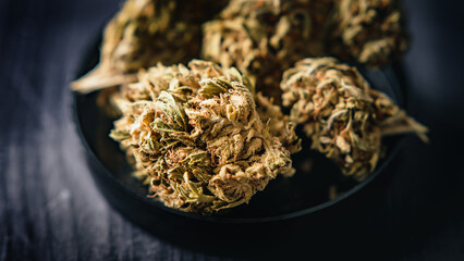 Dry CBD cannabis, also known as dried hemp flowers, is displayed on a wooden table