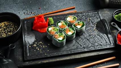 sushi rolls with salmon, kale leaves, and cream cheese. Served with wasabi sauce and pickled ginger. Japanese traditional food. Close up.