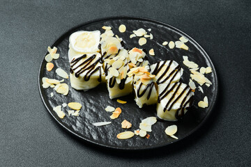 Appetizing sweet sushi rolls with banana and chocolate. Sushi set on a table.