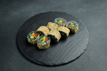 Appetizing sushi rolls with wild rice, salmon, cucumber and avocado. Sushi set on a table.