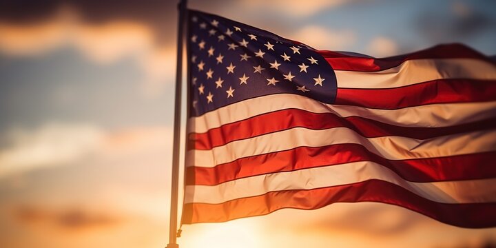 The flag of the United States of America flutters in the wind in the soft light of the sunset.