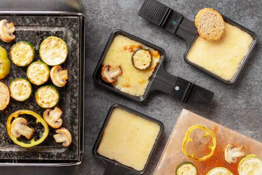 Delicious traditional Swiss melted raclette cheese on diced boiled or baked vegetables served in individual skillets.
