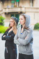 Two young millennial sportive woman wearing tracksuit arms crossed