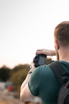 Bearded young man taking pictures of urban area train station in the sunset. negative space to place your text above.