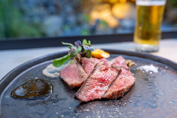 テラス席で食べる美味しそうな牛肉ステーキとビール