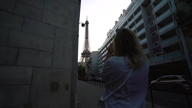 Back view of young female using smartphone to taking photos of Eiffel tower in Paris, France.
