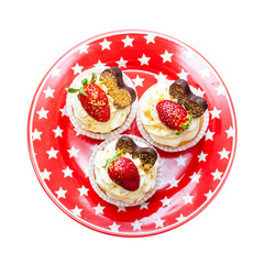 Set of vanilla cupcakes decorated with fresh strawberries, blueberries, chocolate hearts and golden sprinkles on red star plate