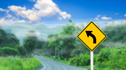 Right curve directional arrow on yellow sign on blurred road and mountains background concept of warning people driving safely                               