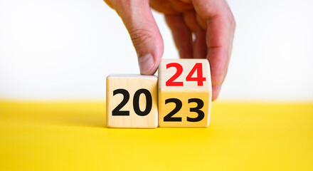 Business concept of 2024 new year symbol. Businessman turns a wooden cube and changes number 2023...