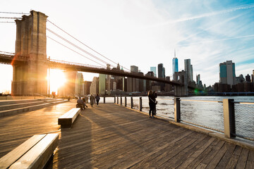 View of Brooklyn Bridge with Lower Manhattan in the background, lit by sunset