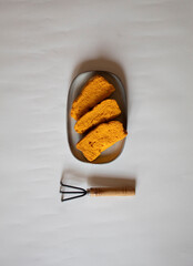 Yellow rusks with a small garden fork on a white background minimal flat lay