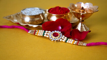 Indian festival: Raksha Bandhan background with an elegant Rakhi, Rice Grains and Kumkum Raksha bandhan with sweets gifts flowers and diya