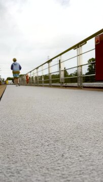 Senior Female Jogging on a Track. Surface level views of a mature woman jogging on a walking track. The walking track is located on the top deck of a moving boat. She is dressed casually.