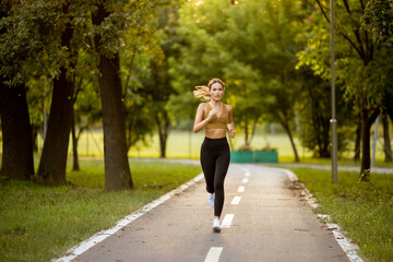 Pretty young woman running on the lane in the park