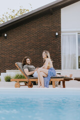 Young couple relaxing by the swimming pool in the house backyard