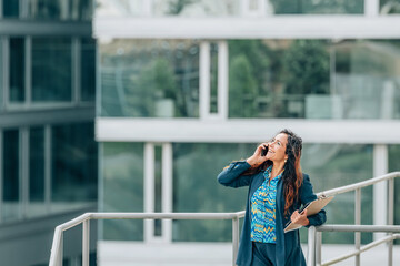 business woman talking on mobile phone in the street with office background