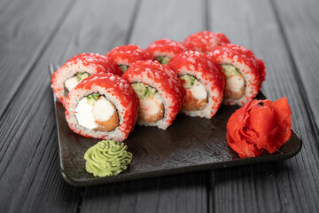 Sushi rolls with masago caviar on black stone plate on wooden background, japanese food concept, sushi menu