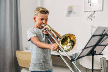 A young boy is committed to practicing trombone.