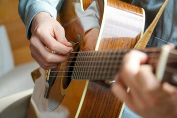 Fototapeta premium Melodic Mastery: Close-up of someone's hands skillfully playing a guitar, capturing the essence of musical creativity.