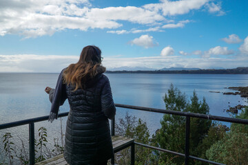 A bundled-up woman dancing solo on a terrace overlooking a lake, embracing the music in her headphones on a chilly day.