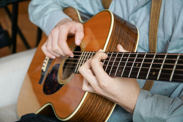 Fototapeta na wymiar Strings of Melody: Close-up view of anonymous hands skillfully strumming a guitar, creating harmonious notes.