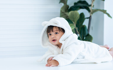 Adorable caucasian little baby daughter girl, wearing cute white bathrobe, taking bath in morning,...