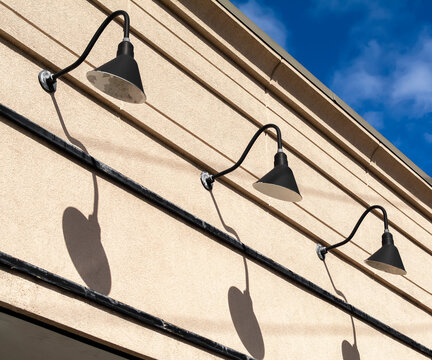 Row of gooseneck lights with their shadows on storefront wall