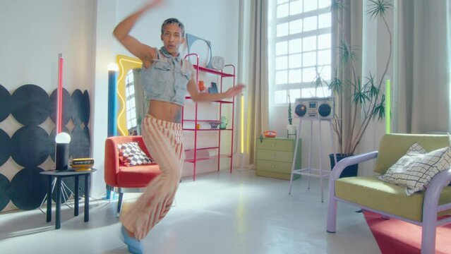 Energetic lgbtq dancer with leopard print hair wearing colorful visible thong, y2k outfit and high heels vogueing and jumping during performance in studio. Zoom shot