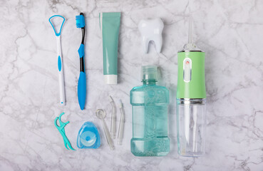 Electronic oral irrigator, toothbrush, paste, dental floss and mouthwash on marble background. Dental tool for oral hygiene. Electric Interdental Cleaner. Dental water shower. Oral care concept. 