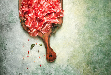 Prosciutto on a cutting board, top view, appetizer, breakfast, spices and herbs,