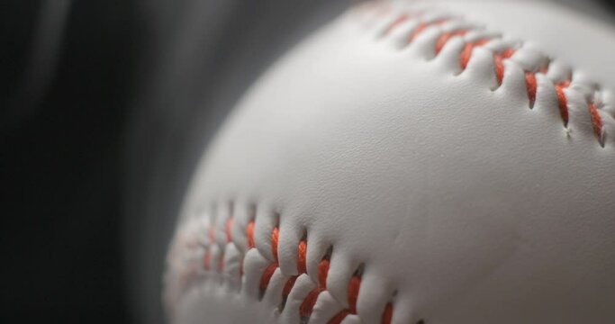 Baseball ball close up rotating in studio with smoke in slow motion