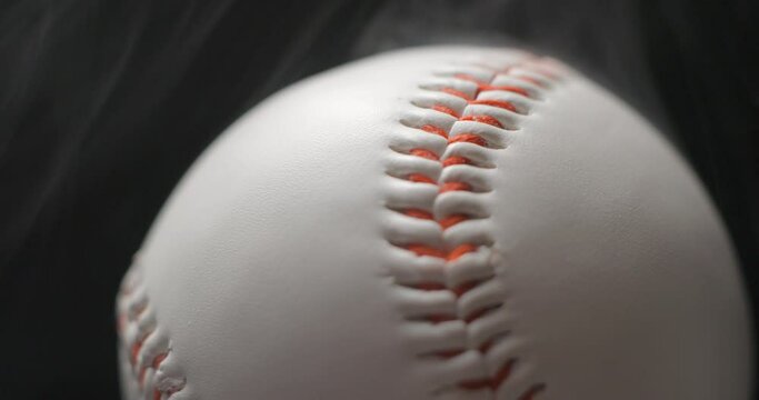 Baseball ball close up rotating in studio with smoke in slow motion