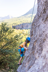 Child rock climber. The boy climbs the rock. The child is engaged in rock climbing on natural terrain. Sports kid spends time actively.
