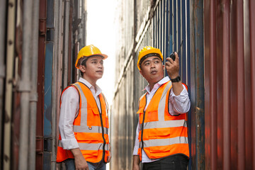 Asian container worker talking on walkie talkie to control work quality at dock. import export shipping business. freight cargo and logistic warehouse concept