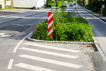 Greenery on the edge of street for forced speed reduction in the city with vertical warning sign
